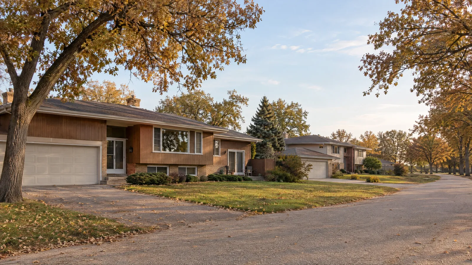 1970s ranch and split-level homes on wooded lots under bronze bur oaks in autumn