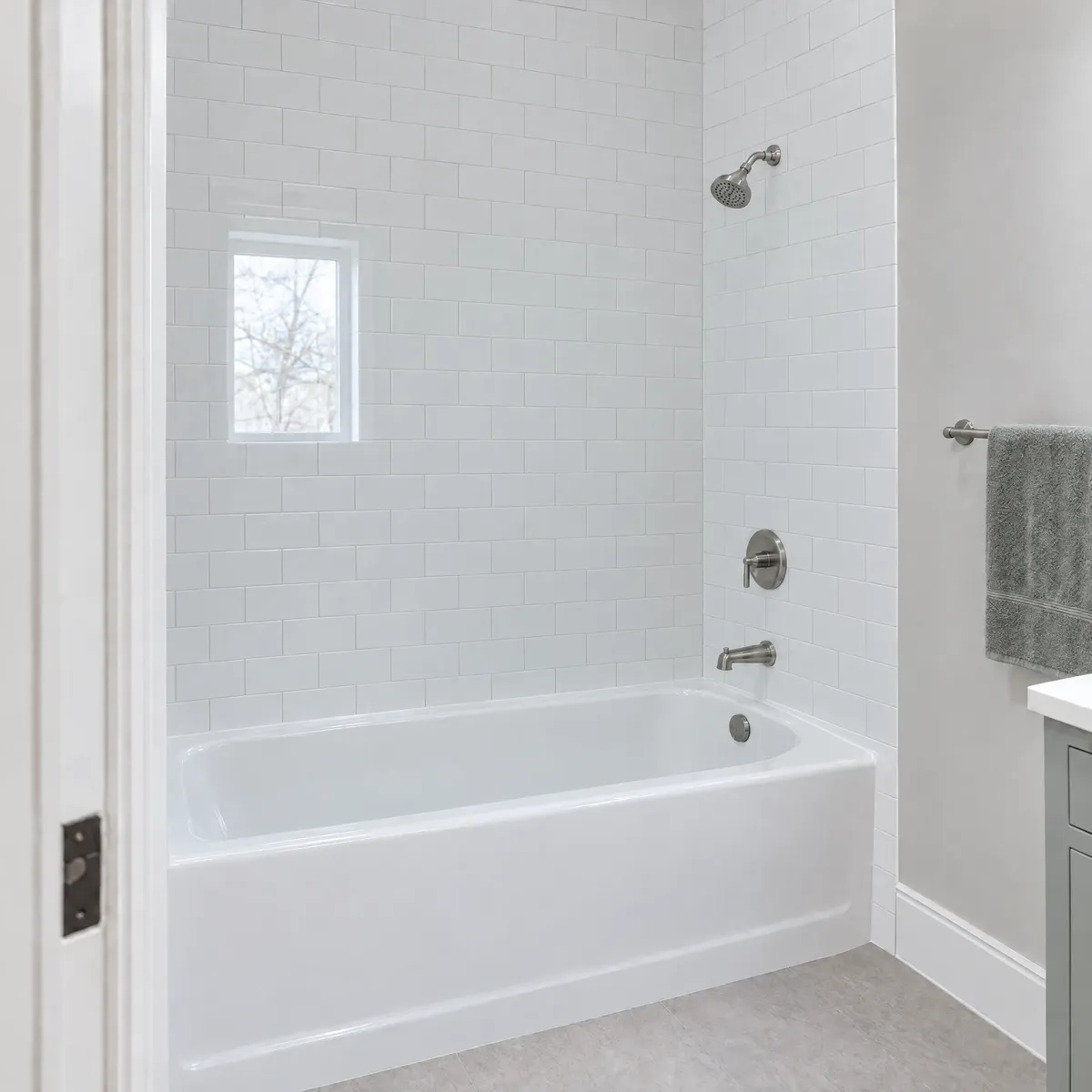 White bathtub in a subway-tile alcove with no glass doors
